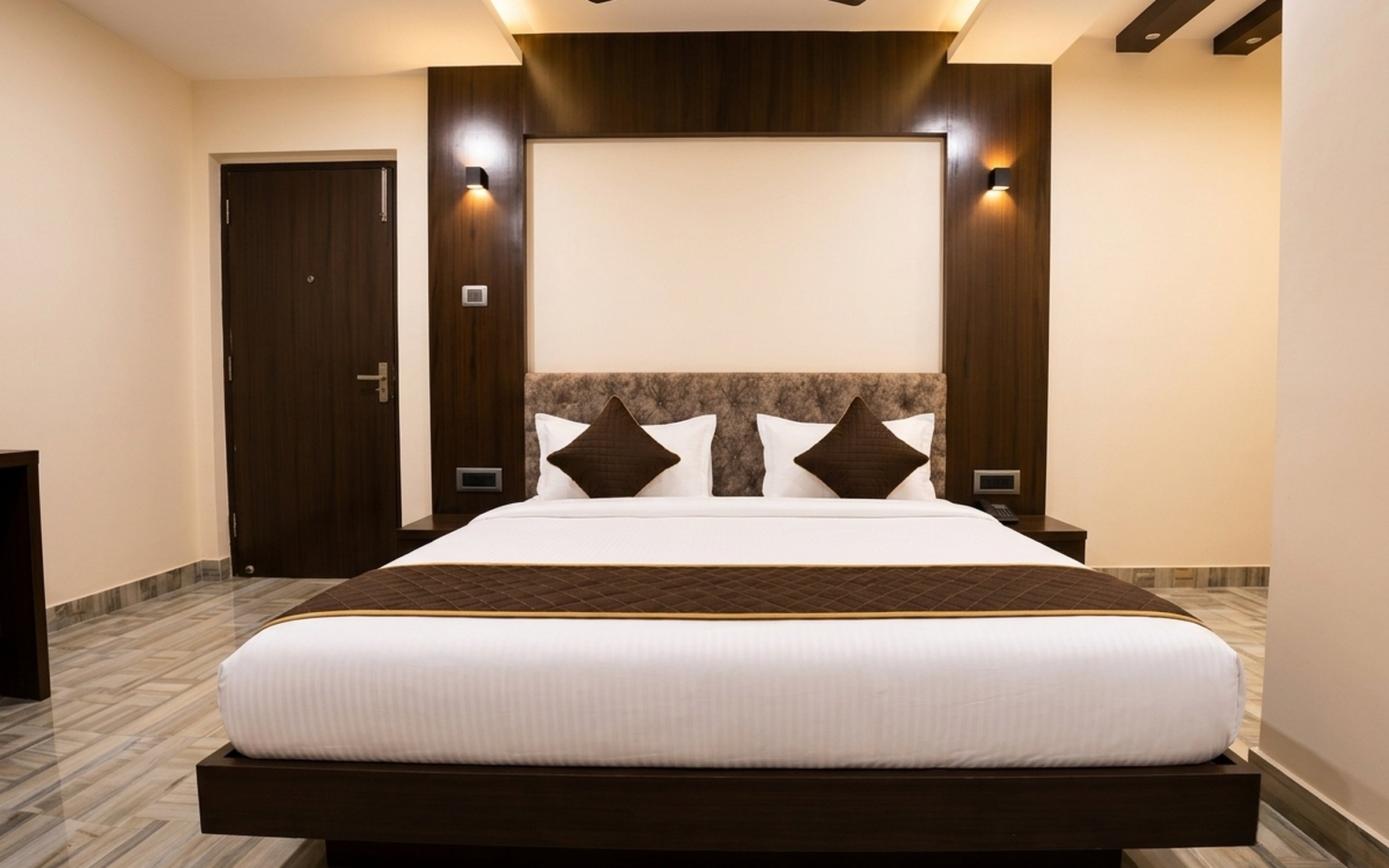 A Superior room at Hotel Magadhi: king bed, upholstered headboard and wood-panelled wall
